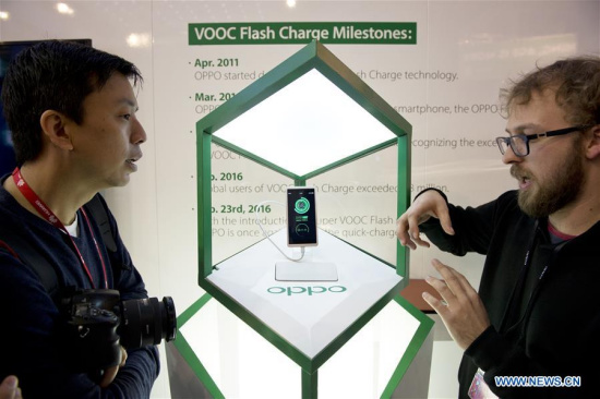 Staff members of Chinese company OPPO display VOOC technology to visistors at the Mobile World Congress in Barcelona, Spain, Feb. 23, 2016. The Mobile World Congress (MWC), the most important mobile communication event in the world, opened its doors in Barcelona Monday. (Photo: Xinhua/Lino De Vallier)