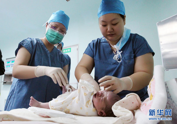 Medical staff put clothes on the newborn test-tube baby at a hospital in Xi'an, Northwest China's Shaanxi province. (Photo/Xinhua)