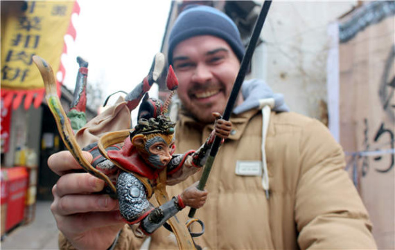 A foreign tourist shows off a dough figurine of monkey at Pingjiang Road in Suzhou.