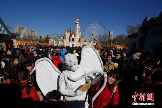 A visitor takes photo with a performer at the international carnival at the Shijingshan park during the Spring Festival in 2014. (Photo: China News Service)