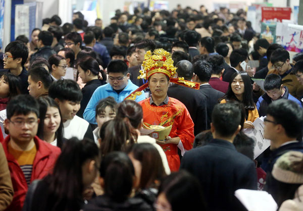 Representing a company, a worker dressed as the God of Wealth from Chinese legend, attracts the attention of job-seekers at an employment fair in Hangzhou, Zhejiang province, on Saturday. The employment outlook is grim as 7.65 million university graduates enter the job market this year.(Photo: China Daily/Lin Yunlong)