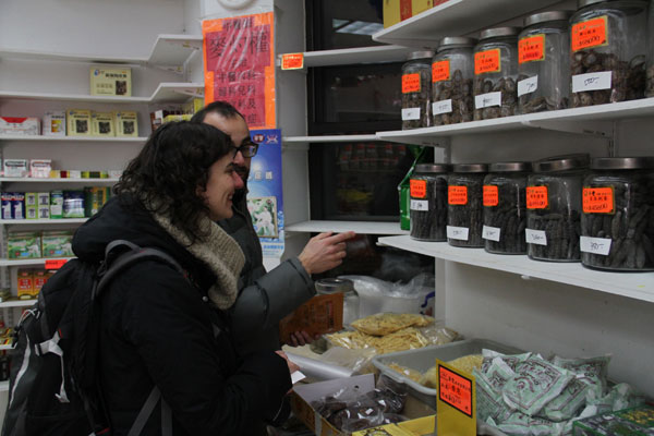 Two visitors from Spain show interest in dried sea cucumber products in a drug & food store at New York's China Town on March 1. Adelina Amado (female in front), said it was her first time to see real cucumbers in life and she would have never expect that the sea cucumbers could be high-end food beforehand. LONG YIFAN/FOR CHINA DAILY