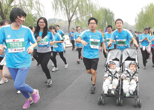 A man runs with his twin sons on the 2014 Hangzhou Marathon. (China Daily/Xu Kangping)