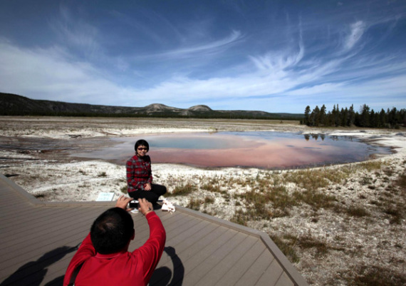 A tourist poses for a photo in front of a spring in Yellowstone National Park, Wyoming, Aug 13, 2011. [File photo: China Daily/Agencies] 