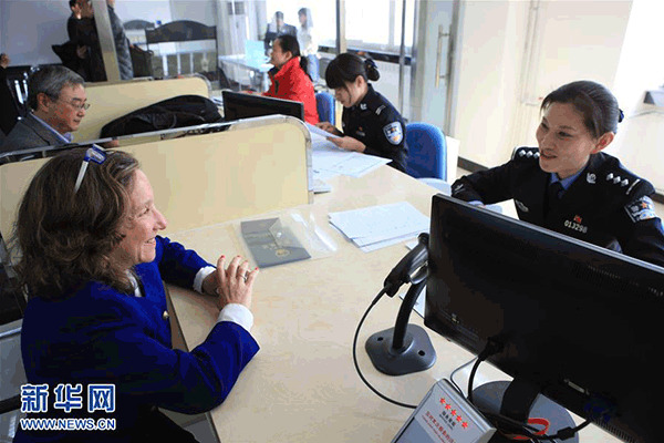 A staff member at Beijing Public Security Bureau's Exit-Entry Department receives an expat on March 1, 2016. (Photo/Xinhua)