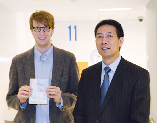 Edmund Downie (left) receives a 10-year tourist visa from Ruan Ping, consul general and counselor at the Chinese embassy in Washington on Wednesday. It was the first 10-year visa issued to an American at the embassy since China and the US reached an agreement this week. Chen Weihua / China Daily
