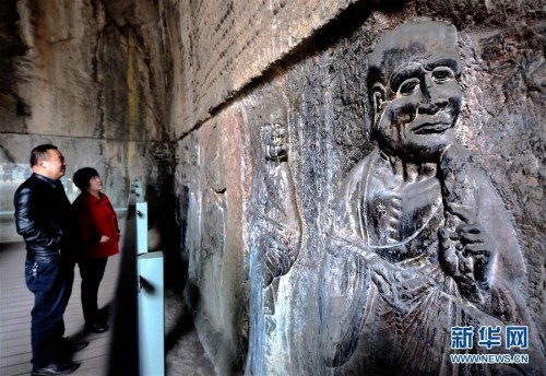 Visitors take photos to an arhat statue created during the Tang Dynasty (618-907) in Kanjing Temple of Longmen Grottoes on March 10, 2016. Longmen Grottoes in central China's Henan Province opened another of its caves to the public on Thursday, giving them the opportunity to see a complete set of 29 arhat statues created during the rule of a Buddhist Chinese empress. (Photo/Xinhua)