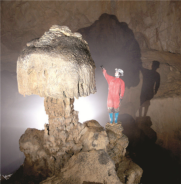 A caver examines a mushroom-shaped stalagmite in a karst cave. Provided to China Daily