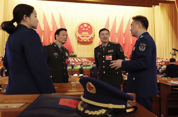 National People's Congress deputies from the People's Liberation Army chat ahead of the third plenary session of the NPC annual session in Beijing on Sunday. XU JINGXING/CHINA DAILY