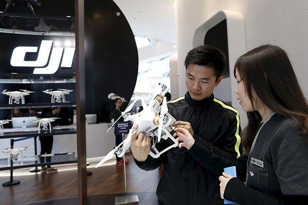 A customer (left) holds a DJI's Phantom 3 Standard drone at the firm's first flagship store in Shenzhen, Guangdong province. (Photo provided to China Daily)