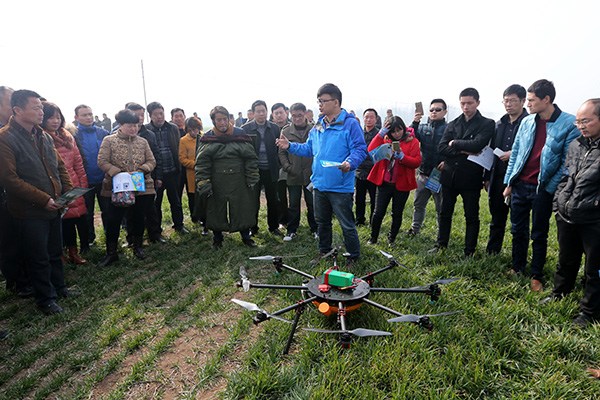 A technician demonstrates to some farmers in Huaibei, Anhui province how to use a drone in farm production. (Photo/China Daily)