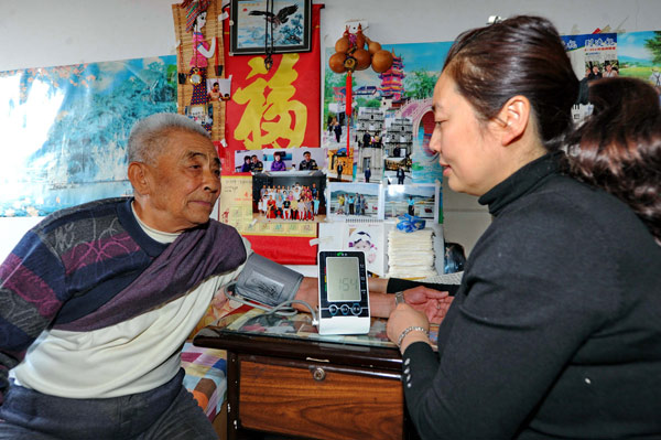 A social worker checks an old man's blood pressure at a residential community in Changchun, Northeast China's Jilin province. (Photo/Xinhua) 