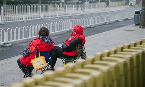 Two women wearing red armbands chat as they keep an eye on a street in Beijing. (Photo: Li Hao/GT)