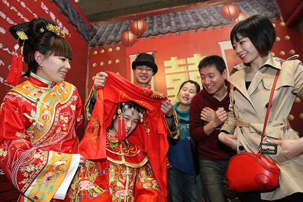 Business promotion staff dress in Chinese wedding clothes to promote folk wedding supplies during a recent wedding fair in Chongqing. (Photo provided to China Daily)