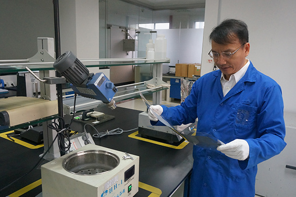 Chen Yu, chief executive officer of OED Technologies, examines the quality of an e-paper product at a workshop of Guangzhou OED Technologies Co in Guangzhou, Guangdong province.  (Photo provided to China Daily)
