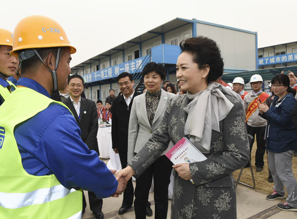 Peng Liyuan, China's first lady and the World Health Organization's goodwill ambassador for tuberculosis and HIV/AIDS, greets a migrant worker in Beijing on March 22 at a publicity event ahead of World Tuberculosis Day, which falls on March 24 each year. (Photo provided to China Daily)