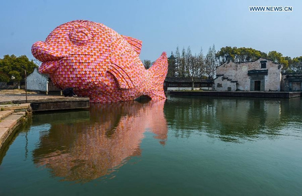 Photo taken on March 27, 2016 shows a giant pink Floating Fish on the water theatre in Wuzhen, east China's Zhejiang Province. The pink Floating Fish is a piece of works designed by Florentijn Hofman, who is also known for creating a huge Rubber Duck in Hong Kong in 2013, for the Wuzhen International Contemporary Art Exhibition. The Floating Fish is made of floating plates for swimming. The exhibition will be held here from March 28 to June 26. (Photo/Xinhua)