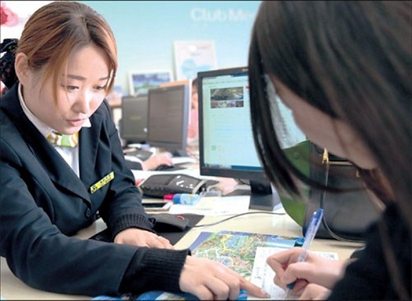 A travel agency staff member helps a customer buy Disney Resort tickets yesterday.(Photo/Xinhua)