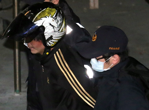 The suspect in a 4-year-old girl's decapitation, Wang Ching-yu (wearing a helmet), is escorted to a detention center in Taipei, Taiwan, on Tuesday.(HUANG SHIQI/CHINA DAILY)