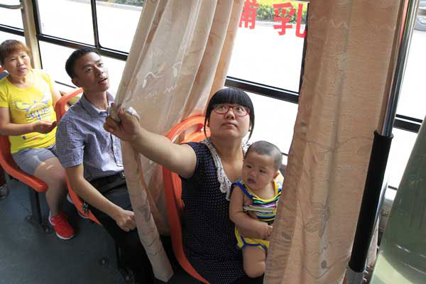 A woman and her son use a special breast-feeding seat on a bus in Zhengzhou, capital of Henan province. The city tested the seats on the No 906 bus and planned to expand the program if the service is well-received. (Photo/China Daily)