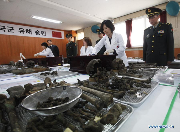 South Korean workers accompanied by Chinese army officers prepare the remains of Chinese soldiers who died in the Korean War in early 1950s, in Paju, South Korea, March 28, 2016. The remains of 36 Chinese soldiers will be flown back to China after a handover ceremony on March 31. (Photo: Xinhua/Yao Qilin)