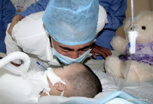 Feng Lei, gives her daughter Feng Junxi a final kiss at a hospital in Beijing, capital of China, June 9, 2012. A couple from Chifeng in north China's Inner Mongolia autonomous region decided to donate their daughter Feng Junxi's body organs after her death.(Photo/Xinhua)