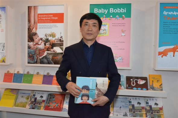 Chinese writer Cao Wenxuan poses with his works at the Bologna Children's Book Fair in Bologna, Italy, on April 4, 2016. Chinese children's fiction writer Cao Wenxuan on Monday won the Hans Christian Andersen Prize 2016 at the Bologna Children's Book Fair in Italy. (Photo: Xinhua/Song Jian)