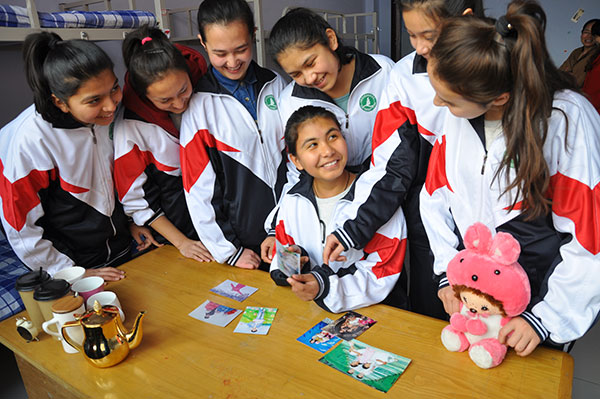 Students from the Xinjiang Uygur autonomous region look at photographs in their dormitory at Rizhao Experimental High School in Shandong province. A total of 49 Xinjiang students, including 19 from different ethnic groups, have studied at the school since October 2014. LIU MINGZHAO/CHINA DAILY