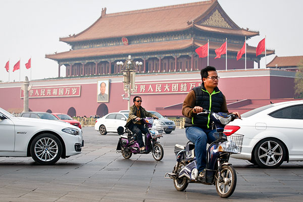 People ride electric bikes on Chang'an Avenue in Beijing on Tuesday. The avenue is one of 10 roads where the bicycles will be banned starting on Monday. Kuang Linhua / China Daily