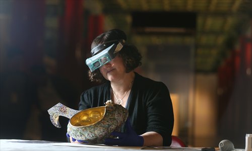 A representative from the Virginia Museum of Fine Arts examines an enamel bowl that once belonged to the Russian royal family on Wednesday at the Palace Museum in Beijing. (Photo: Cui Meng/GT)