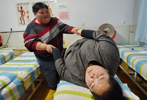 Lin Yue, 29, helps his wife, Deng Yang, get up at a hospital in Changchun, Jilin province, in December. The couple turned to doctors in hope of having a baby after their weight increased from less than 100 kilograms each in 2010, when they got married, to nearly 200 kg. (Photo/Xinhua)