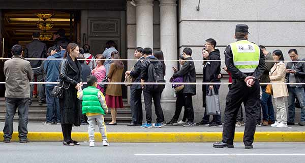 People in Shanghai wait in line on Sunday to buy bidding documents in the monthly auction to get local license plates for private vehicles.Zhu Weihui / For China Daily