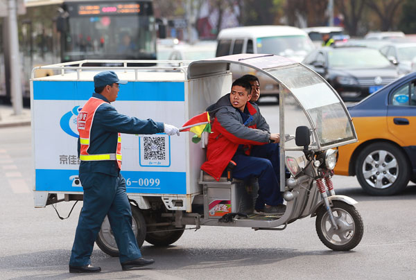 A traffic warden intercepts an electric tricycle in Beijing on April 11, 2016. The capital imposed a ban that bars electric bikes and tricycles from 10 roads, including Chang'an Avenue and some of its connecting roads. Drivers will be fined 20 yuan ($3.10) for using the roads, and their vehicles will be seized if they refuse to pay the fine. (Photo by Zou Hong/China Daily)