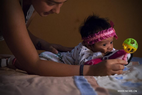 Image taken on Feb. 27, 2016 shows Angela Martinez, playing with her daughter Dominic Andrade (R), who suffers microcephaly, in Quito, capital of Ecuador. Dominic Andrade, 4 months old, permanently receives therapy at home and on the facilities of a hospital due to microcephaly that has affected her since birth. (Xinhua file photo/Santiago Armas)