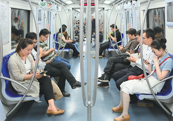 Passengers on a Line 2 subway train in Beijing turn to their smartphones to read books, magazines, or simply play games, to break up their journeys. (Photo provided to China Daily)