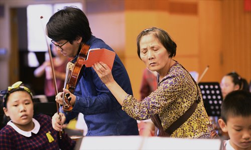 A grandmother records a violin teacher's performance so that her grandson can follow his example and practice at home. (Photo/Courtesy of Jin Siliu)