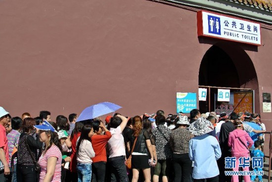 Tourists stand in a long queue outside a toile in Beijing. (Photo/Xinhua)