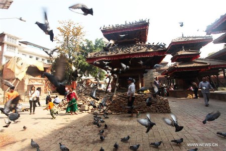 Pigeons fly as people walk past temples at the ruins of Hanumandhoka Durbar Square in Kathmandu, Nepal, April 25, 2016. Nepal is marking the first anniversary of the April 25 earthquake which killed nearly 9,000 people last year. (Photo: Xinhua/Sunil Sharma)