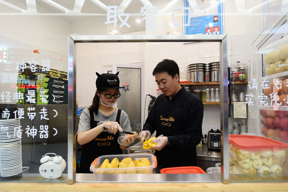 Cui Jianwei works with an employee at a shop in Taiyuan, Shanxi province, April 26, 2016. In order to keep flavors good, all of the ingredients in the ice cream are fresh, Cui said. (Photo/Xinhua)