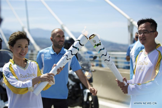Olympic flame torchbearer, Chinese actress Amber Kuo (L) passes the flame to president of the Chinese advertising company Desports Jiang Lizhang during the torch relay of the Rio Olympic Games on Rio-Antirrio Bridge of Greece, on April 22, 2016. (Photo: Xinhua/Jin Yu)