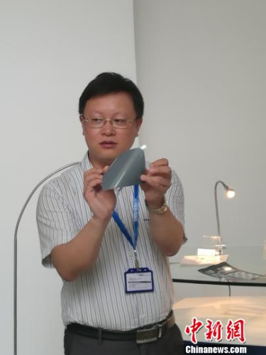 A man shows a piece of graphene electronic paper. (Photo: China News Service/Tang Guijiang)
