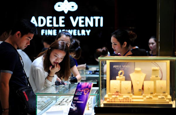 Tourists examine jewelry at a duty-free shop in Sanya, Hainan province. China's luxury market shrank slightly last year. (Photo/Xinhua)