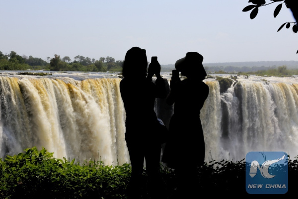 Tourists are seen taking photos of the Victoria Falls, Zimbabwe, Feb. 11, 2016.(Xinhua/Xu Lingui)