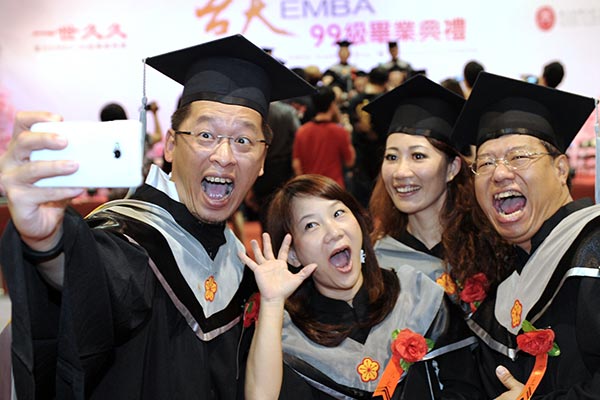 Graduates of the first class of EMBA courses jointly hosted by Fudan University and Taiwan University pose for photos at their graduation ceremony in Shanghai. (Photo/Xinhua)