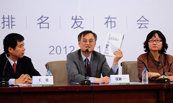 Qian Yingyi (center), dean and professor at the School of Economics and Management of Tsinghua University, holds a book about EMBA rating and development in China. SHEN YUBO / FOR CHINA DAILY