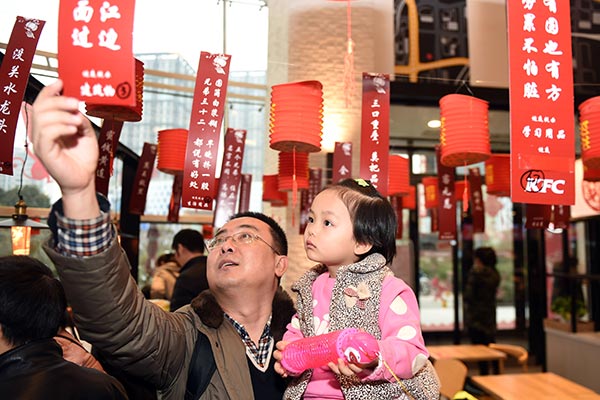 A father and his daughter take part in the riddle-guessing contest at a KFC outlet in Zhengzhou, capital of Henan province, during this year's Lantern Festival. SHA LANG /CHINA DAILY