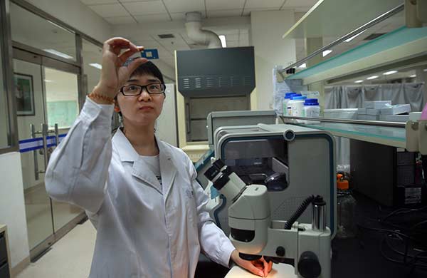 Researcher Xie Lan, chief biochip designer, checks a biochip at the development center in Beijing. Zou Hong / China Daily