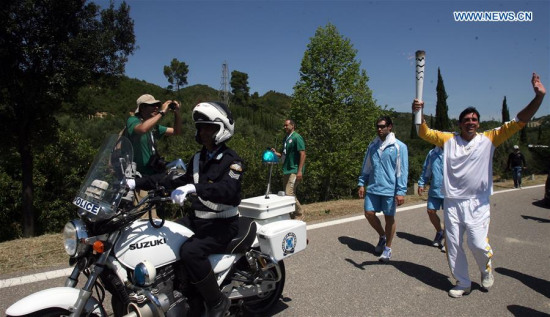 Second torchbearer, Brazilian volleyball player, Giovane Cavio runs with the Olympic flame during the torch relay in ancient Olympia, Greece, on April 21, 2016, after the lighting ceremony of the Olympic flame in Olympia. (Photo: Xinhua/Marios Lolos)