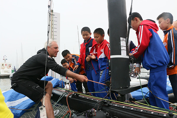 A sailor teaches children how to maneuver the boat during an exchange program.(Photo provided to chinadaily.com.cn)