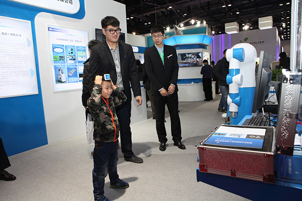 A boy interacts with a robot, developed by Beijing-based Aerospace Science and Industry Intelligent Robot Co Ltd, at an industrial fair in Beijing. (Photo provided to China Daily)